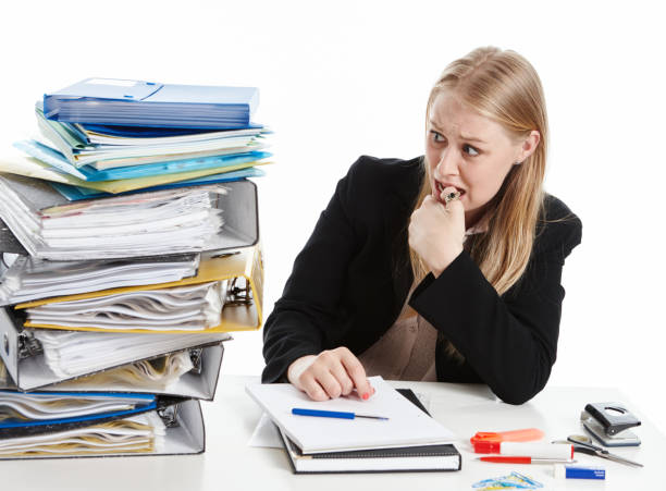"Frustrated school administrator surrounded by papers, calculators, and filing systems, representing the challenges of manual fee tracking.